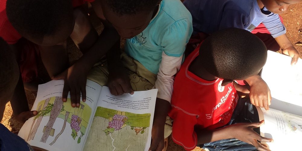 Children from the home reading together! The together part is so beautiful!
